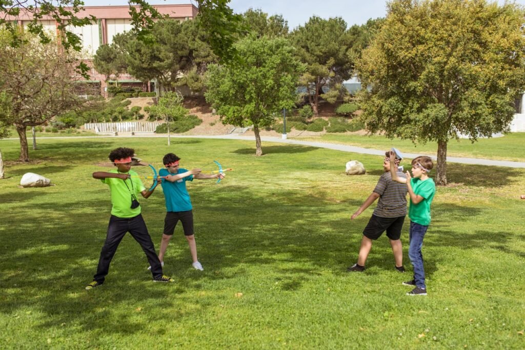 Kids engaged in an outdoor game using toy bows at a summer camp park.